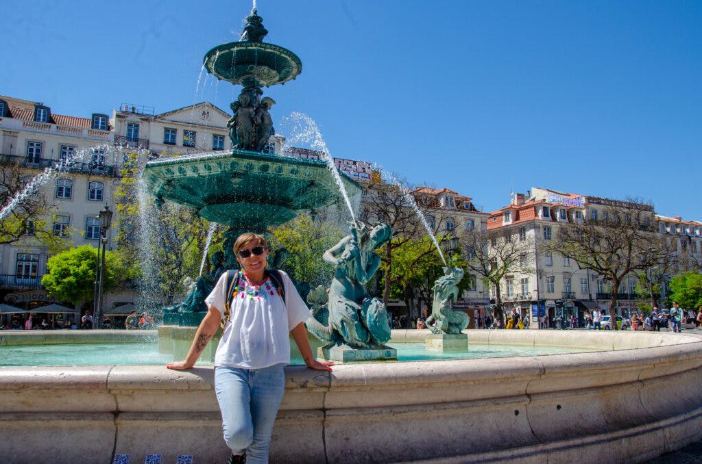 A girl standing at the fountain on the square in Lisbon. 
