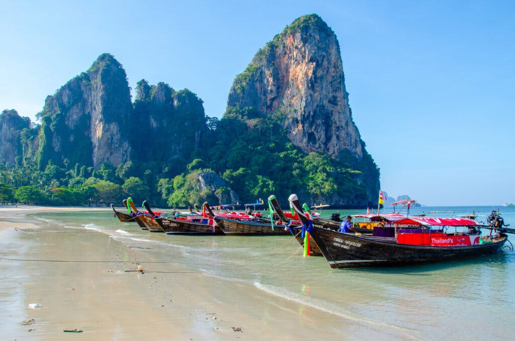 Kolorowe łódki w Tajlandii na tle klifów stoją na plaży i czekają na turystów. 