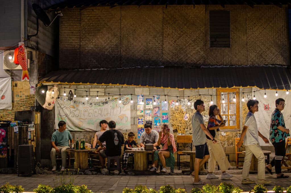 A group of young Thai people sitting and eating at the Mae Kha Market, Chiang Mai.