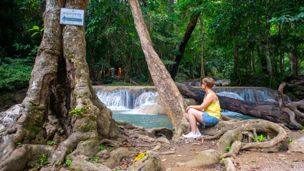 Kobieta siedzi przy wodospadzie Erawan w Tajlandii. 