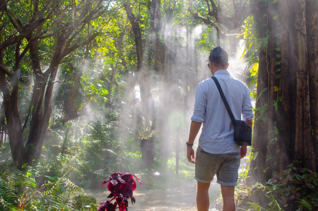 A man walking though mist in Dentewada Land of Angels Waterfall Park. 
