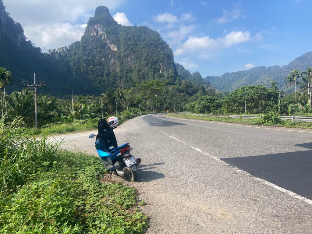 skuter na poboczu, na tle gór w khao sok park.