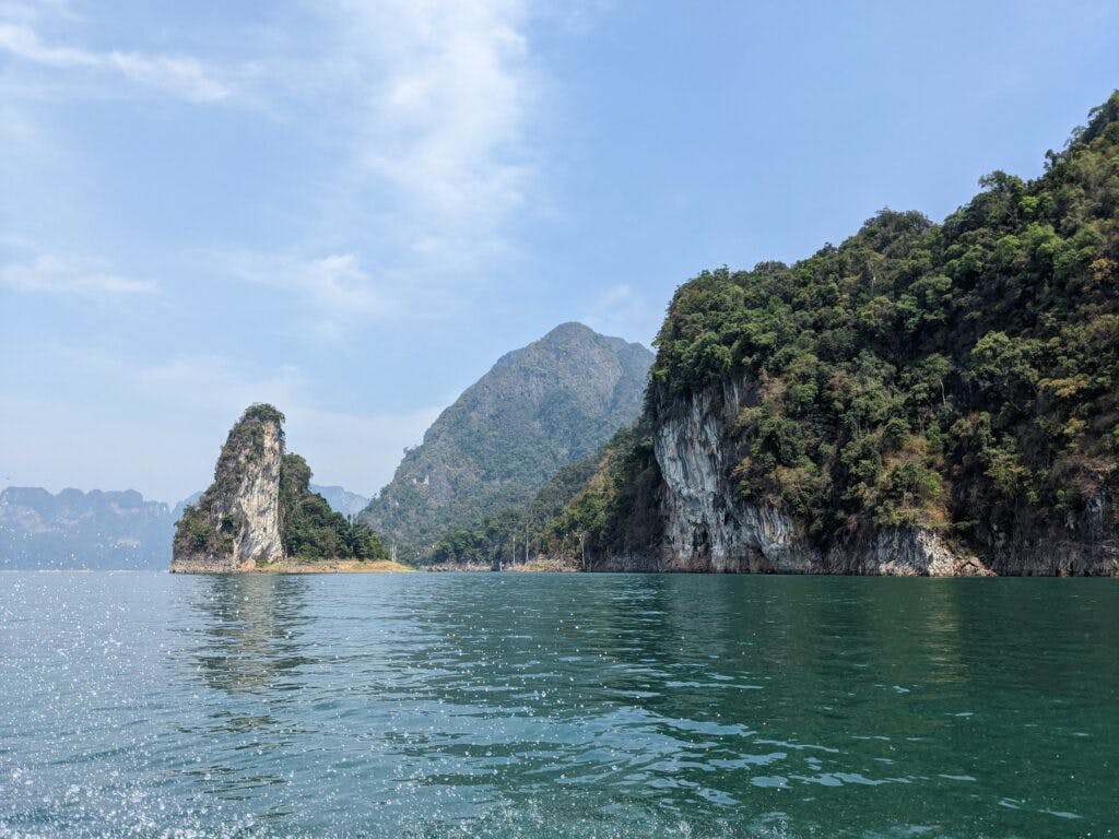 Widok z łódki na jezioro w parku khao sok, skały wystające z wody.