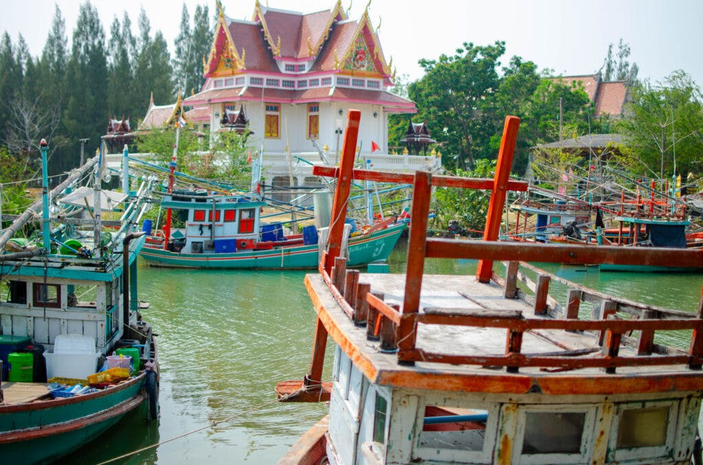 A temple at the river and fishing boats seen from the other side of the shore. 