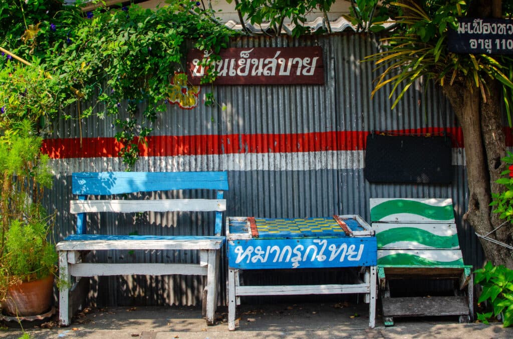 Colourful benches standing against metal fence in thailand.