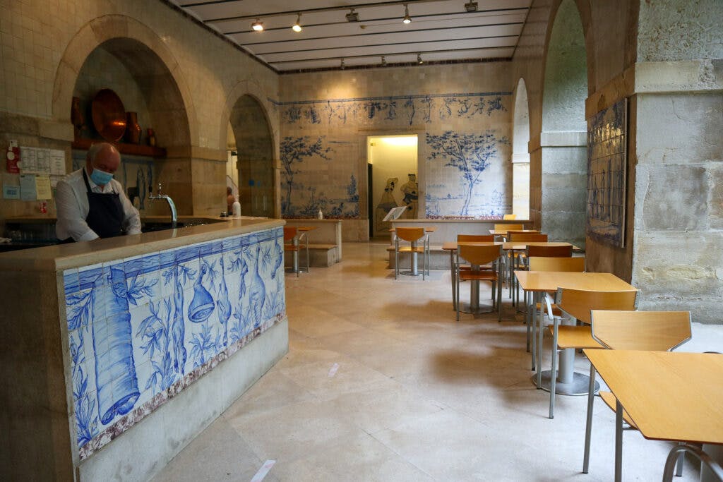 Restauracja w muzeum azulejos w Lizbonie. Niebieskie płytki i małe stoliki, oraz pan za ladą. 