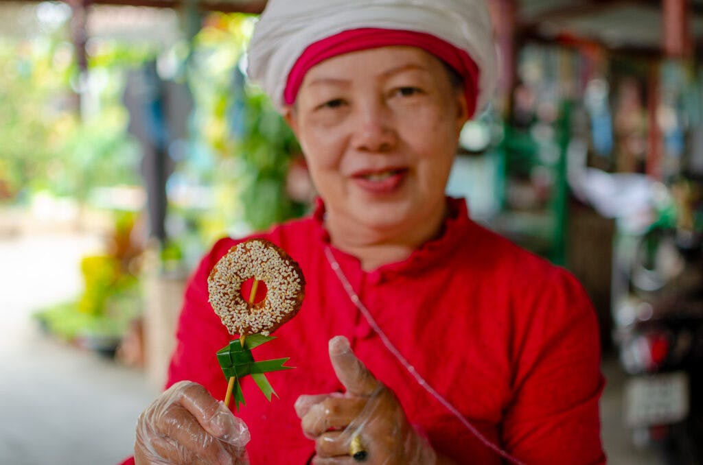 Thai donuts on a stick, lady shows them. 