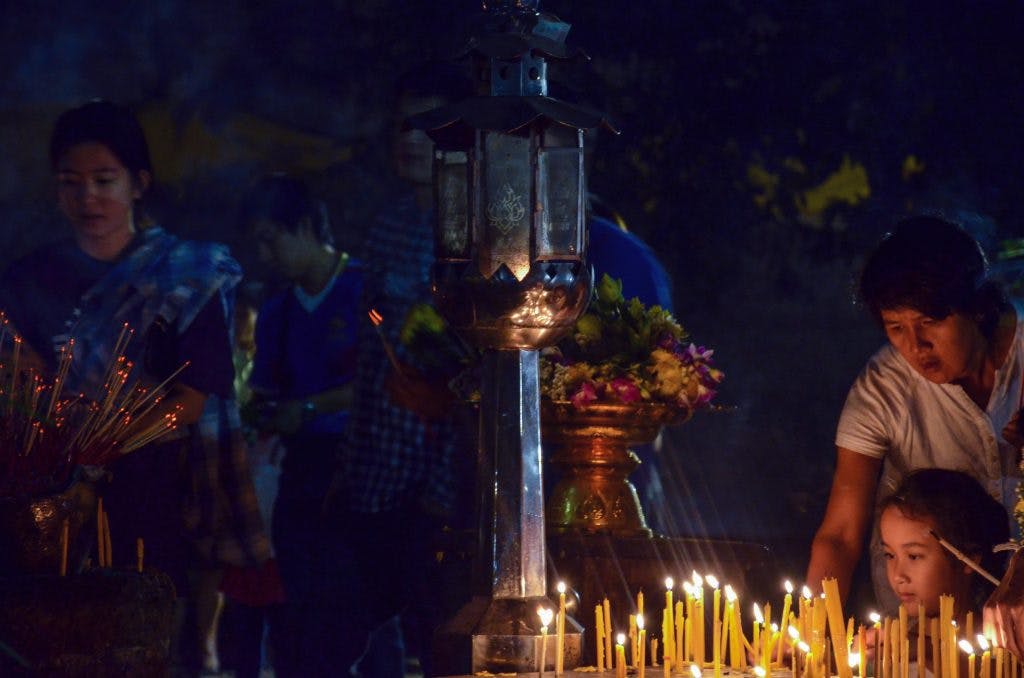 Father and child lighting a candle during Makha Bucha in Chiang Mai