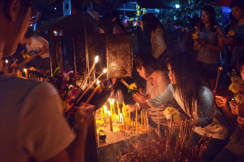 Woman lighting a candle during Makha Bucha in Chiang Mai