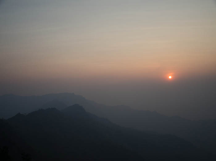 phu chi fa mountain range with the sun shining in the distance 