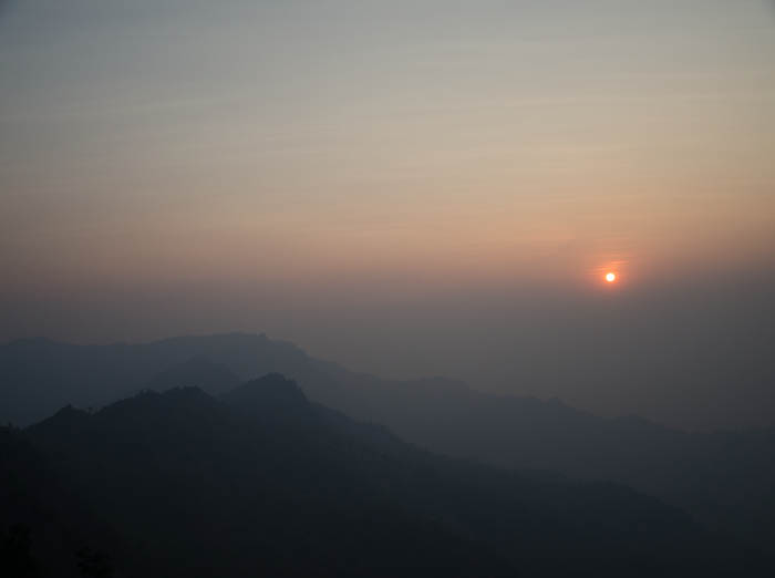 phu-chi-fa-mountain-chiang-rai-thailand-sunrise phu chi fa mountain range with the sun shining in the distance