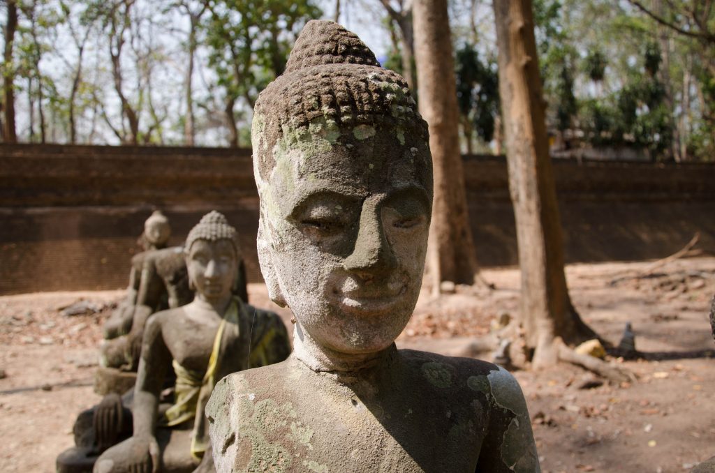 Przed świątynią znajdują się stare i zniszczone posągi Buddy 