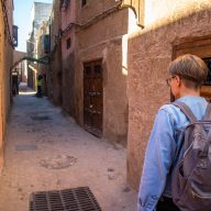 a girl in a jeans jackets walks in an alley in marrakesh