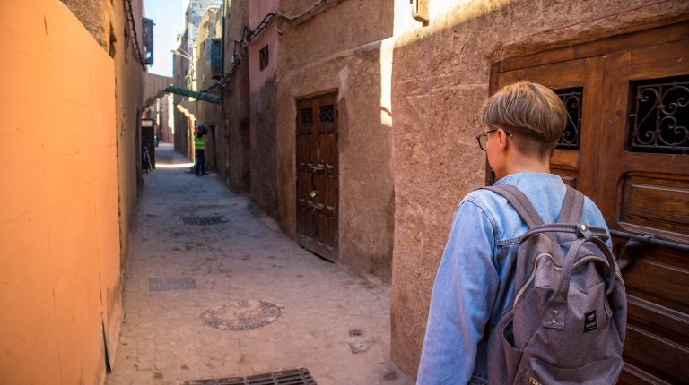 a girl in a jeans jackets walks in an alley in marrakesh