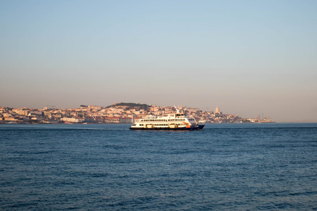 a ferry from cais do sodre to cacilhas cruises through tag river at sunset