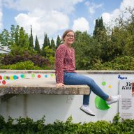 dziewczyna siedzi na murku w Jardim Botânico O Chāo das Artes z szerokim usmiechem