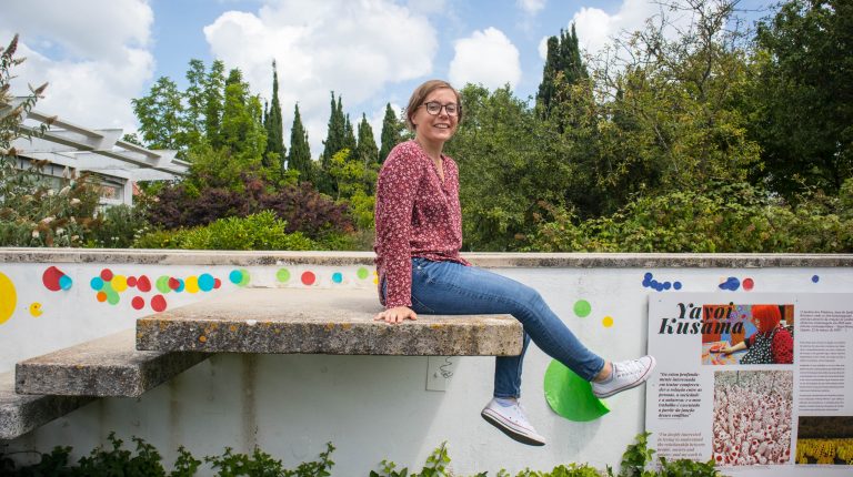 dziewczyna siedzi na murku w Jardim Botânico O Chāo das Artes z szerokim usmiechem
