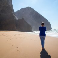 dziewczyna odchodzi w strone slonca na plazy adraga w portugalii