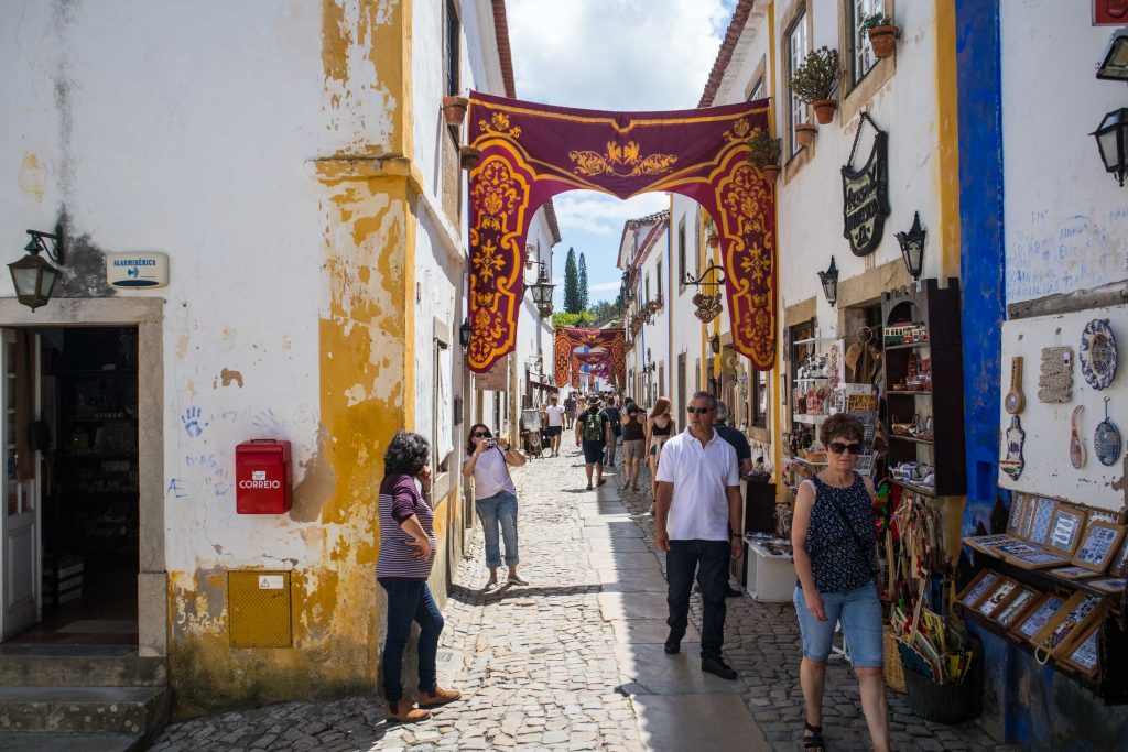 a street in obidos with hanging banners and people walking
