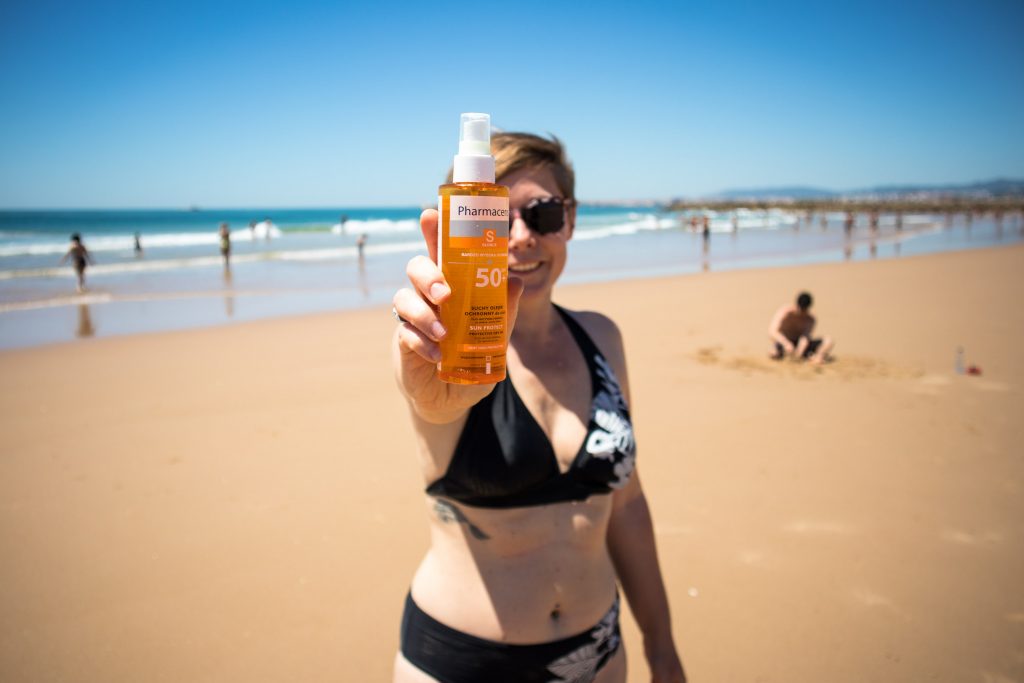 a girl holding pharmaceris spray on the beach in lisbon 