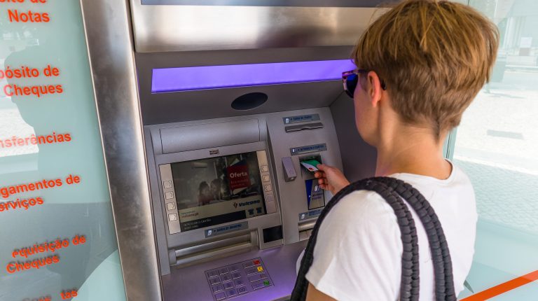 dziewczyna wyciąga gotówkę z bankomatu kartą monese w Portugalii