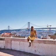 dziewczyna w żółtej sukience siedzi na murku w lizbonie