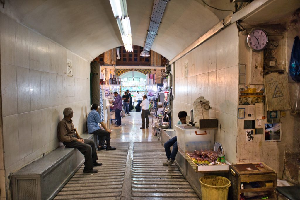 men sitting and watching people in grand bazaar teheran