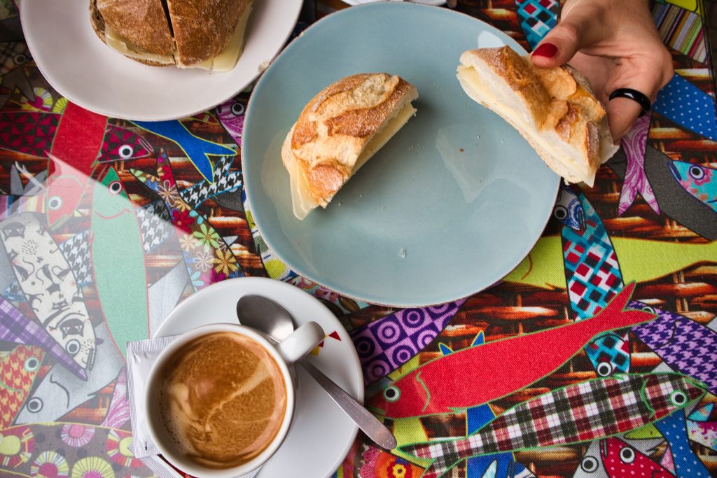 portuguese breakfast bread roll with cheese and coffee served on a colourful table cloth