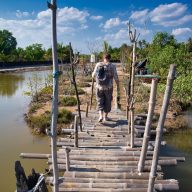 a woman walks on a wooden bridge in koh klang, krabi, thailand