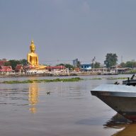 a golden buddha statue over a river in bangkok, koh kret, thailand