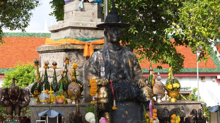 a sculpture of a king of thailand surrounded by colourful flowers in nakhon si thammarat