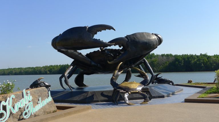 a huge crab sculpture standing on a shore of a river in krabi town, thailand.