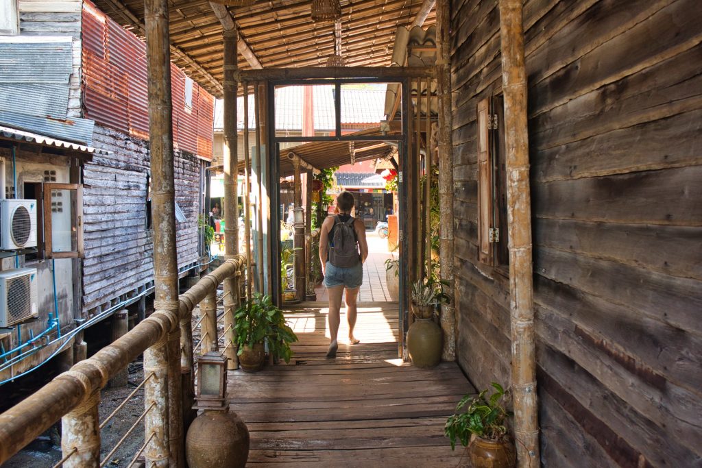 a woman walking on a wooden bridge in the old town in koh lanta. 