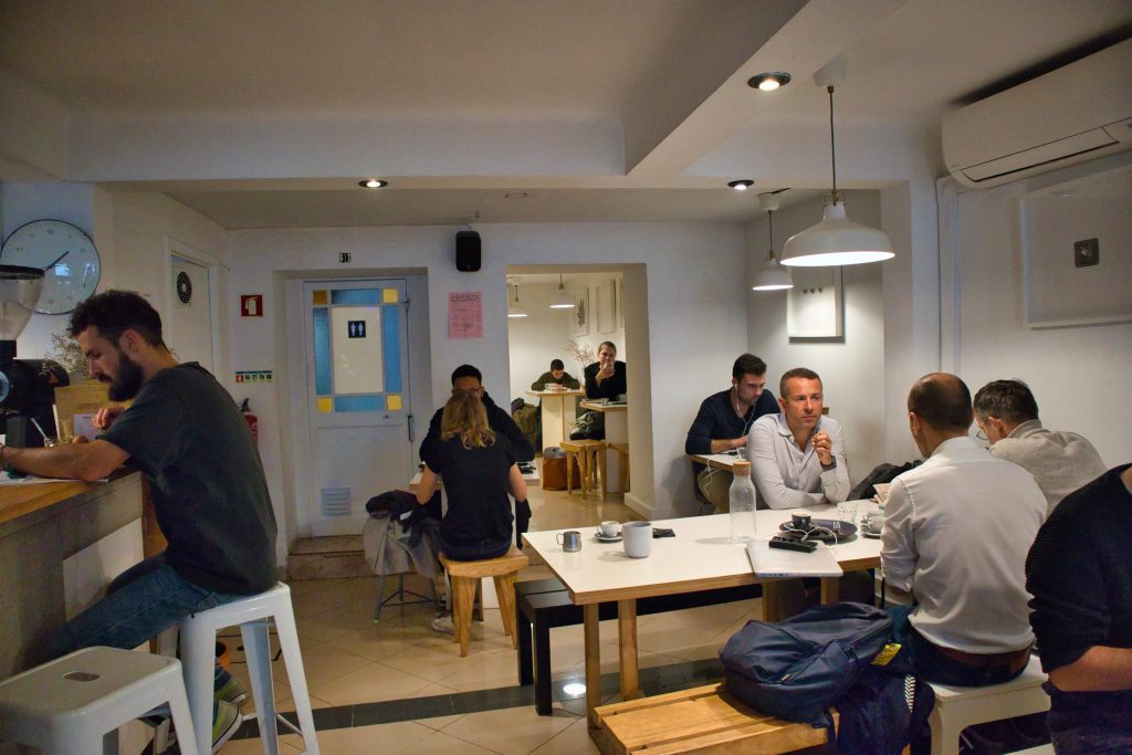 Ludzie siedzą przy stolikach w kawiarni w Lizbonie.