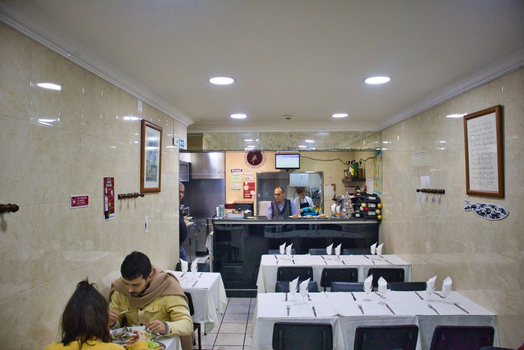the inside of a tasca. empty bar and a lonely couple eating.