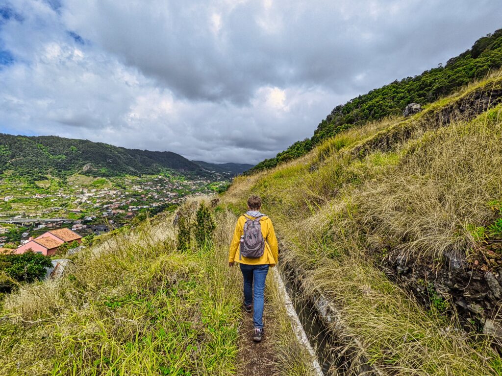 madera-lewada-treking Dziewczyna w żółtej kurtce idzie lewadą na Maderze.
