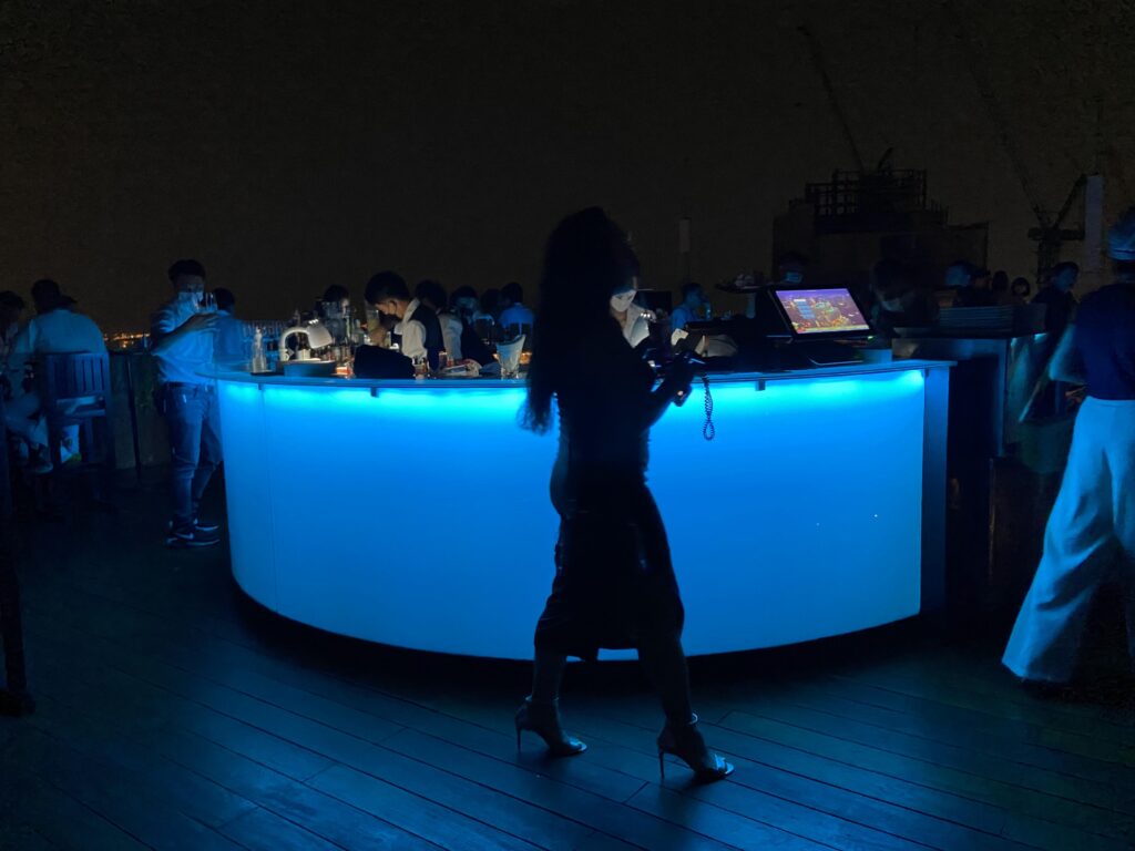 rooftop w bangkoku Rooftop w bangkoku. Kobieta na wysokich obcasach przechodzi obok baru.