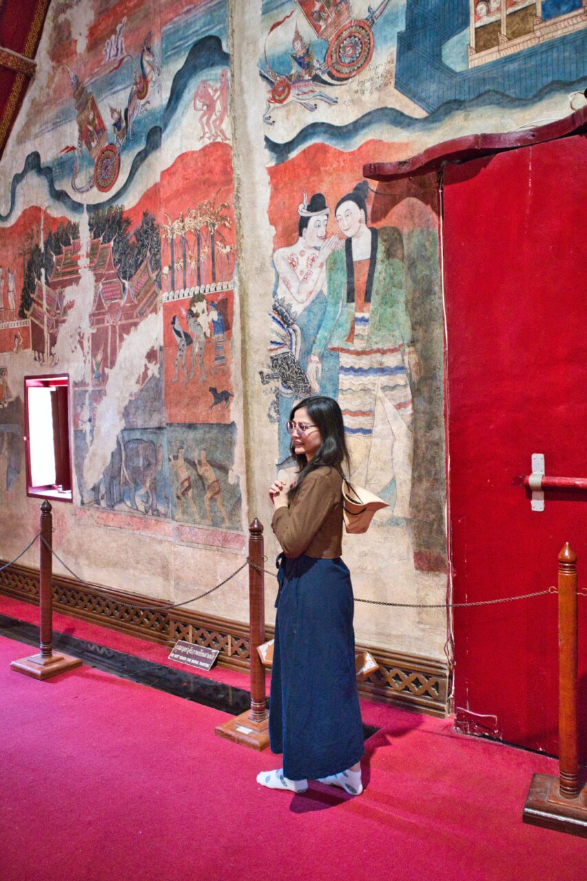 dziewczyna stoi przed freskiem w świątyni nan, tajlandia.