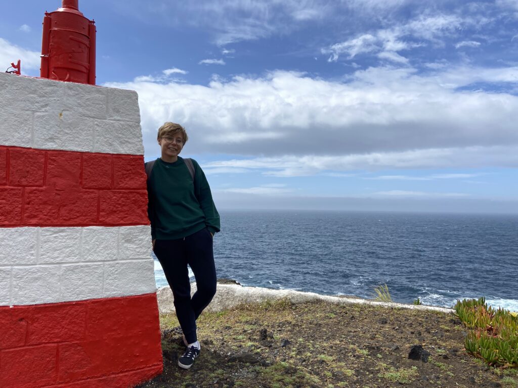 Dziewczyna stoi pod latarnią morską na wyspie terceira.