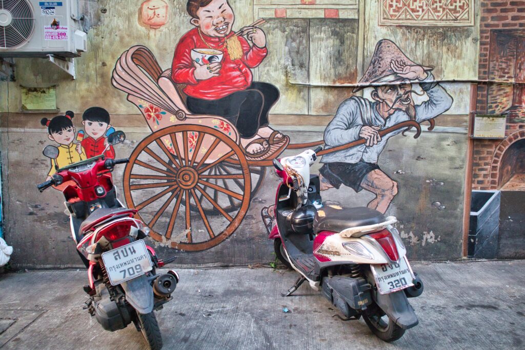 a grafitti showing an old man pulling a cart in talad noi, bangkok