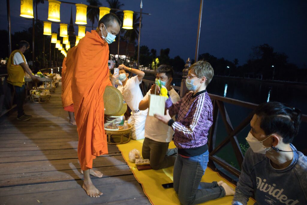 A tourist performs morning alms in Sukothai.