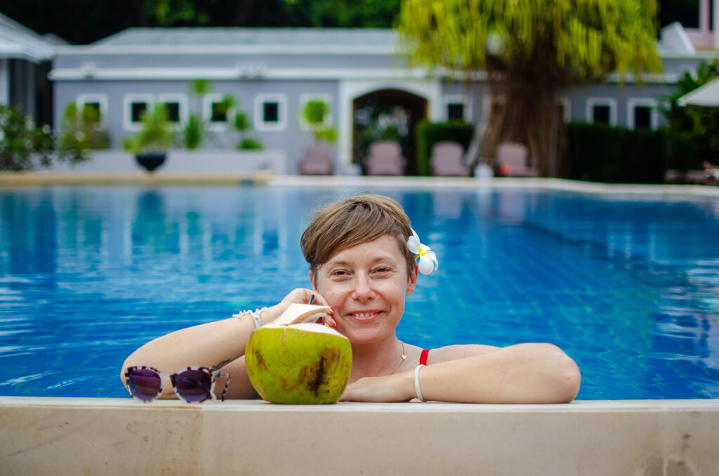 A girl with a coconut in a swimming pool. 