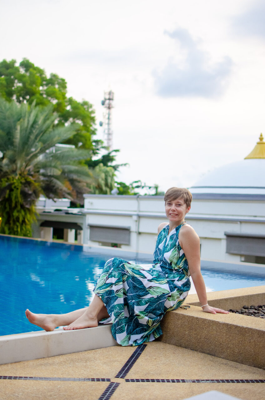 A woman in a blue, green and white dress sits at the pool, absolute sanctuary, koh samui.