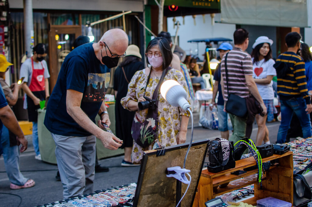 Starsza para ogląda towar na nocnym markecie w Chiang Mai.